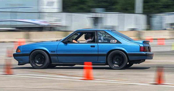 blue fox body mustang in motion on the drag race course